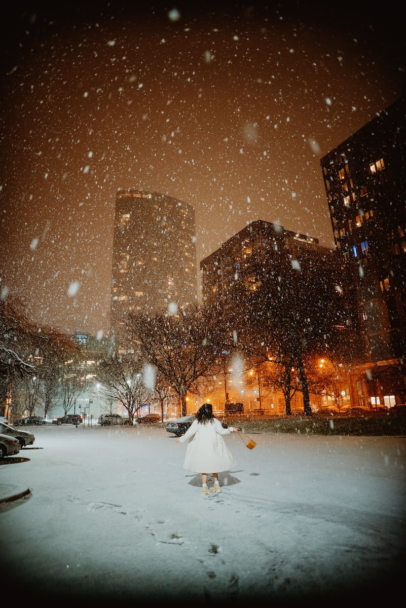 a woman is walking through the snow at night